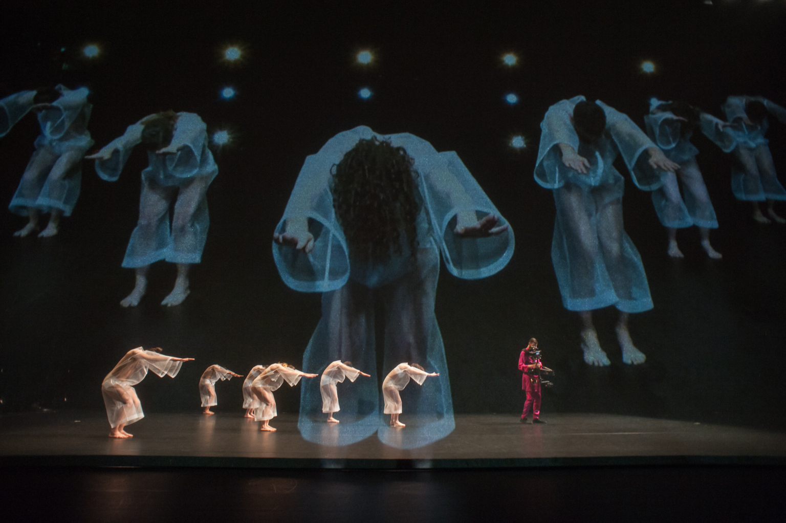 Performance photo of Tesseract show with multiple performers and video elements